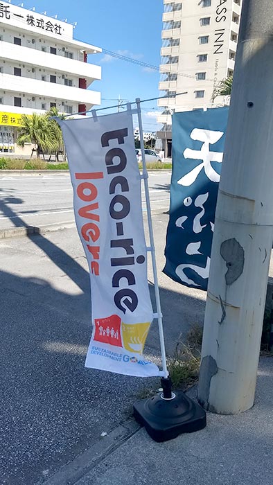A banner sign outside a Taco Rice Lovers' partner's store, welcoming any child to eat at their establishment.
