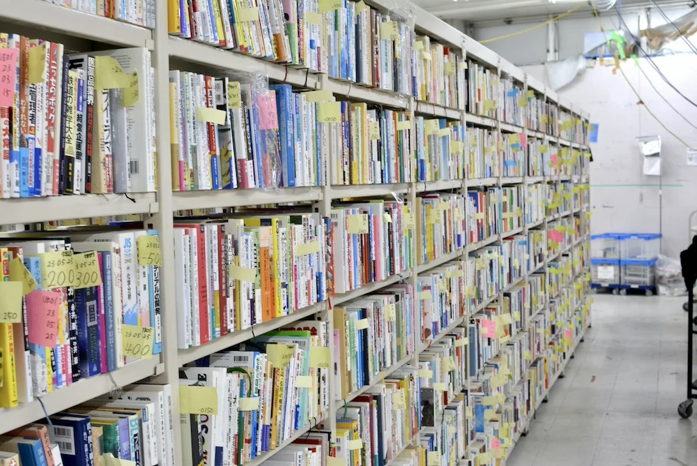 Shelves of books for sale, managed through an online system and handwritten sticky notes